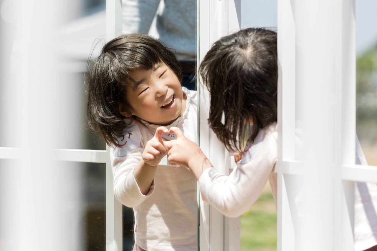 [写真]作品の花壇の内側の鏡を覗き込む子どもの笑顔が鏡に反射して見えています